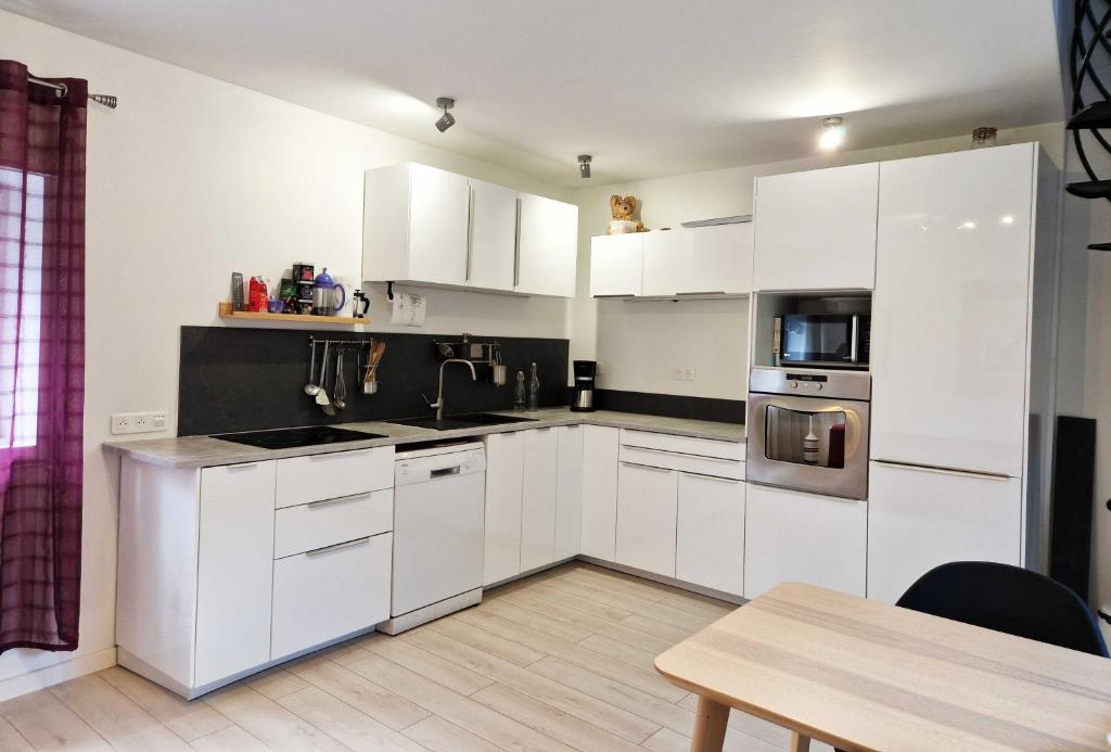 uma cozinha branca com armários brancos e uma mesa em Studio, chambres, appartement, gite em Vendegies-sur-Écaillon