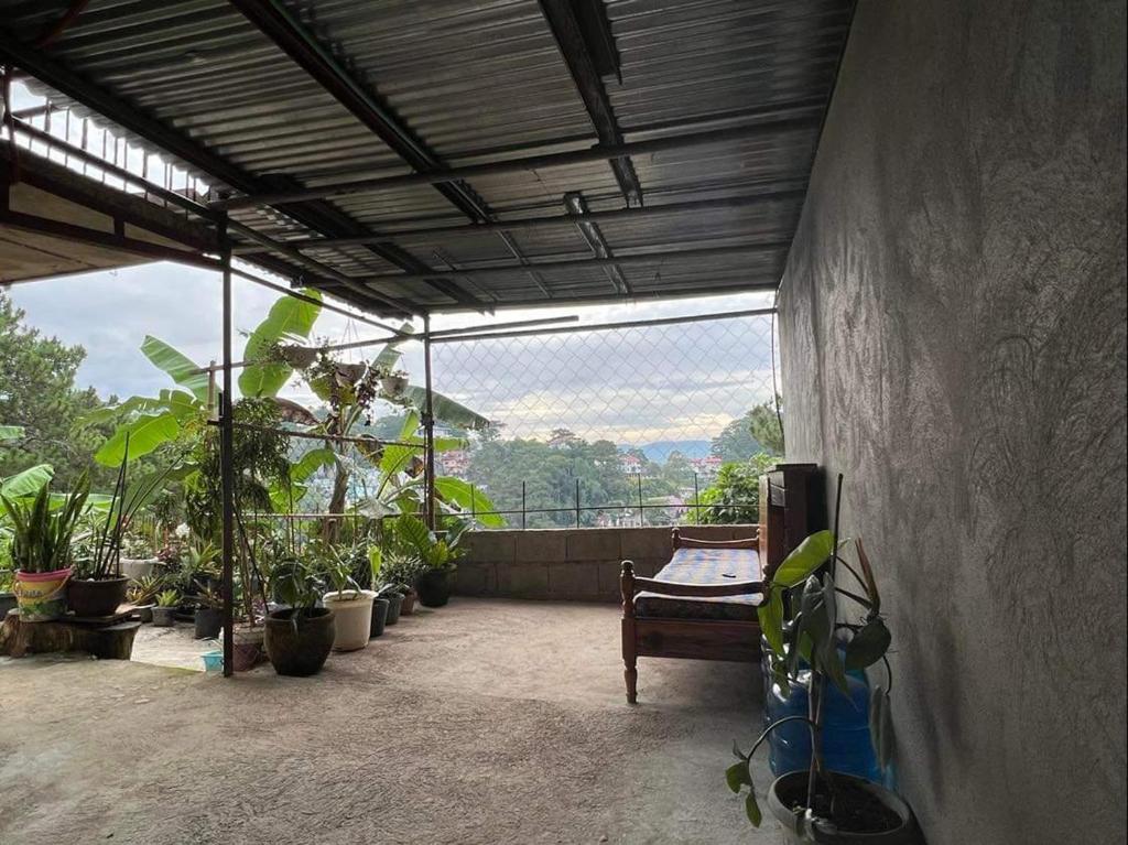 un balcón con plantas, un banco y una ventana en Serenity House en Baguio