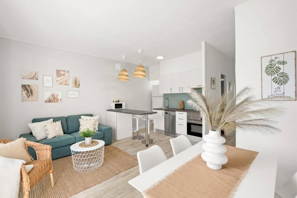 ein Wohnzimmer und eine Küche mit einem blauen Sofa und einem Tisch in der Unterkunft Ca Nostra Apartment in Cala en Porter