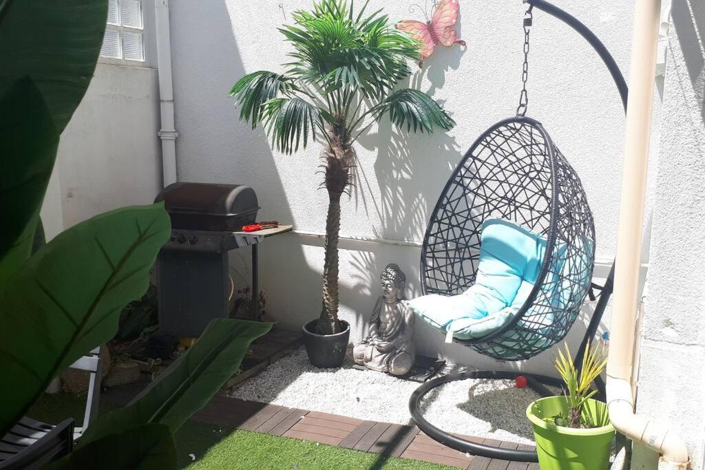 une terrasse avec une chaise et un palmier dans l'établissement Maison plein centre ville La Roche Sur Yon, à La Roche-sur-Yon