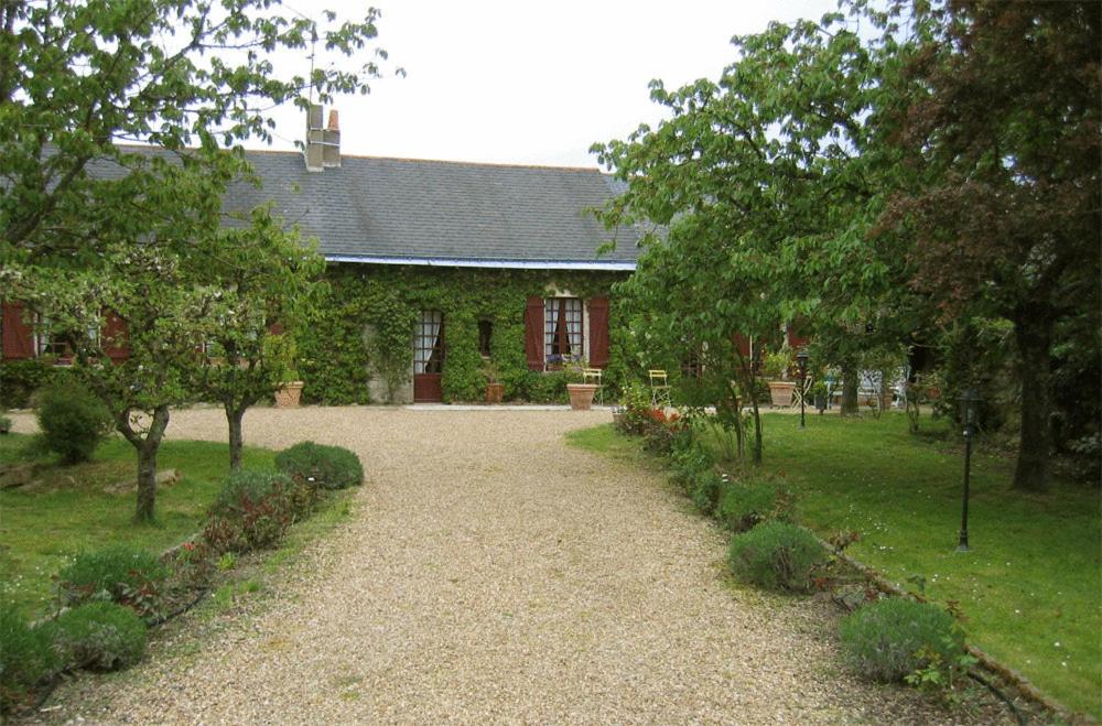 ein Haus mit einem Hof mit Bäumen und einer Auffahrt in der Unterkunft La Poiriere in Chemellier