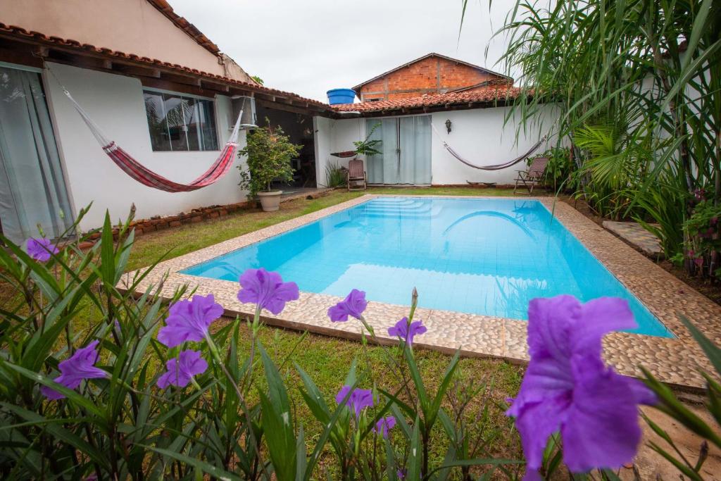 a swimming pool in front of a house with purple flowers at Sertões Hospedaria & Cultura in Carolina