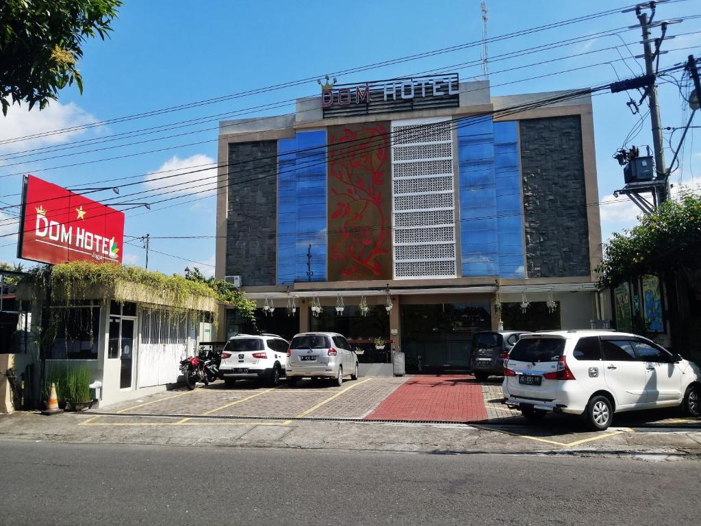 a parking lot with cars parked in front of a building at DOM Hotel Jogja in Yogyakarta