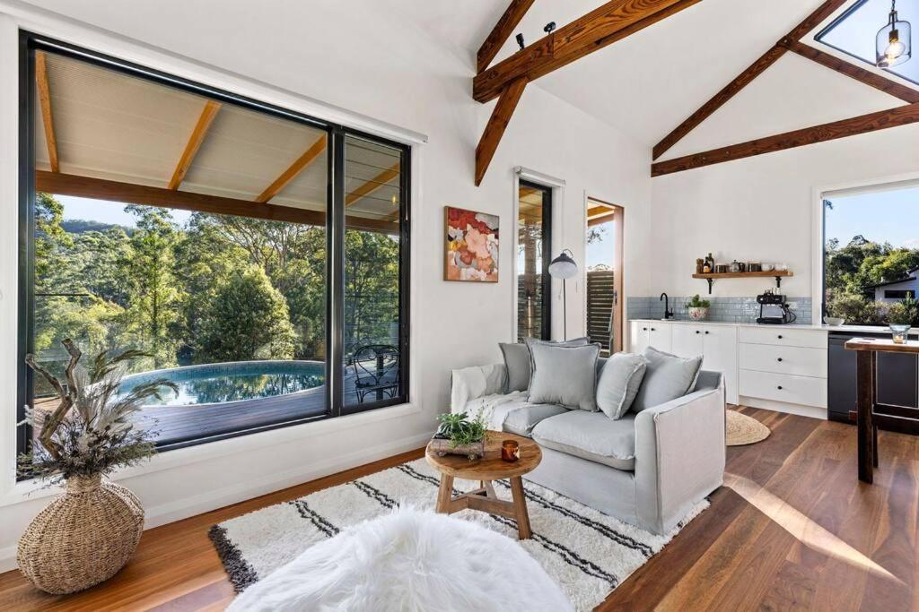 a living room with a couch and a table at Pool House Bellingen in Fernmount