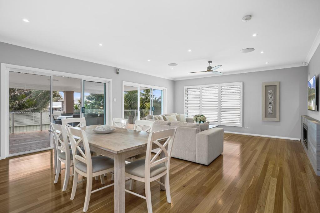 a dining room and living room with a table and chairs at Little Lake Beach House - Beachside 4 Bedroom Luxury Home in Lake Illawarra