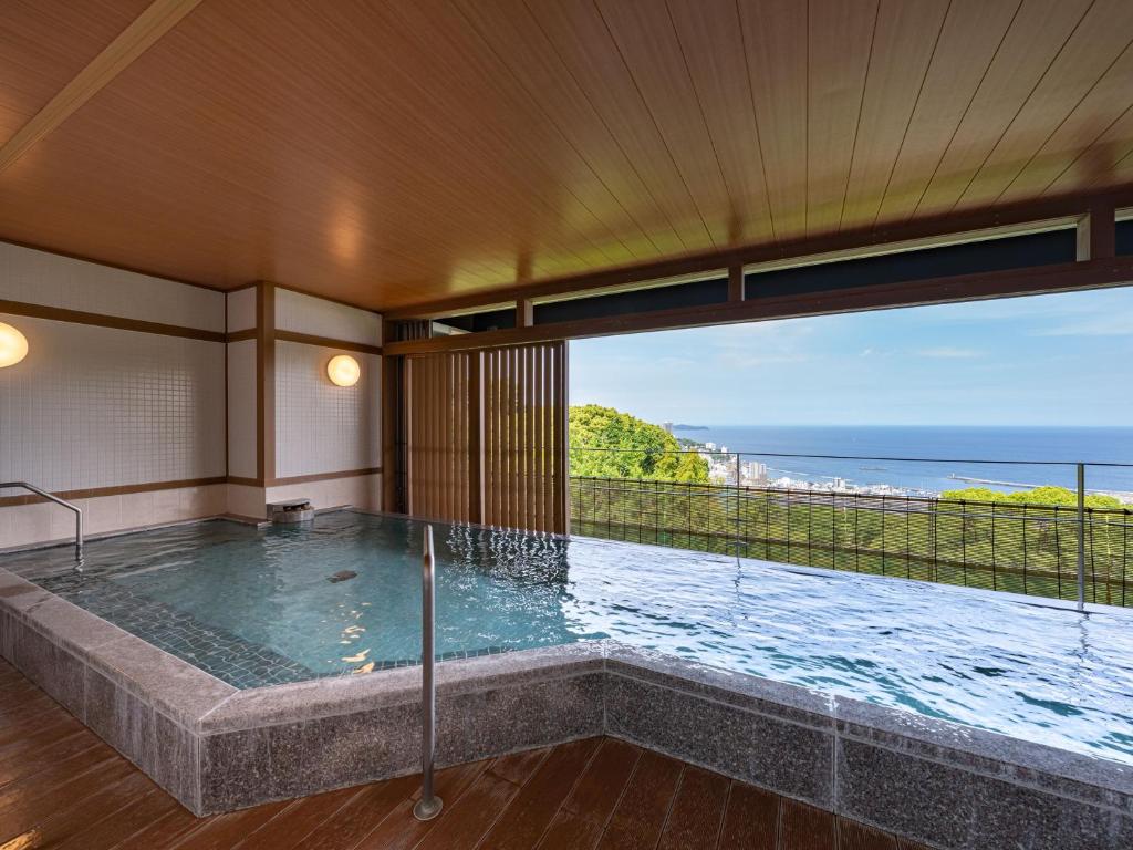a bath tub with a view of the ocean at KAMENOI HOTEL Atami Annex in Atami