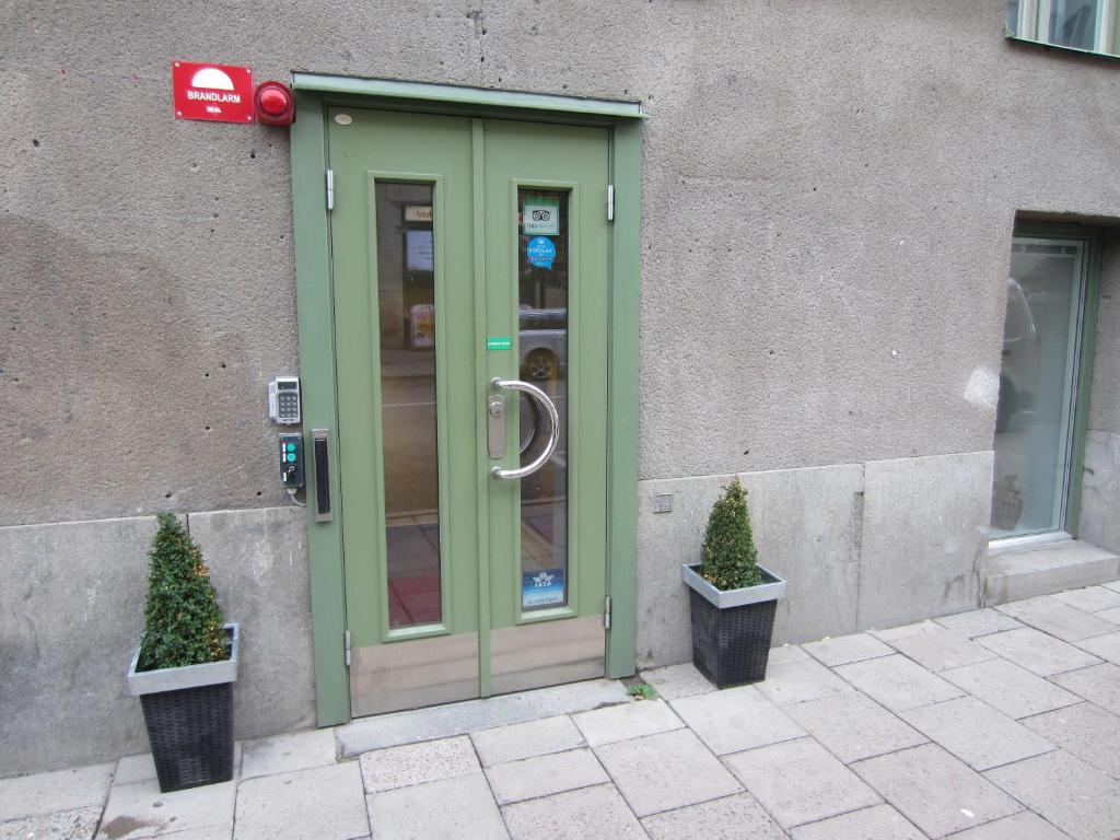 a green door with two potted trees in front of a building at Hostel Dalagatan in Stockholm