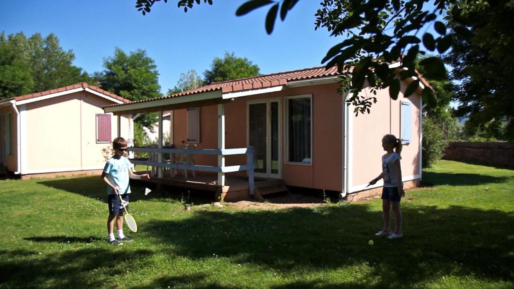 two children standing in the grass in front of a house at Le Hameau des Genets in Montlaur