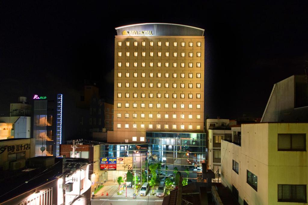 un edificio alto con luces encendidas en una ciudad por la noche en APA Hotel Fukui-Katamachi, en Fukui