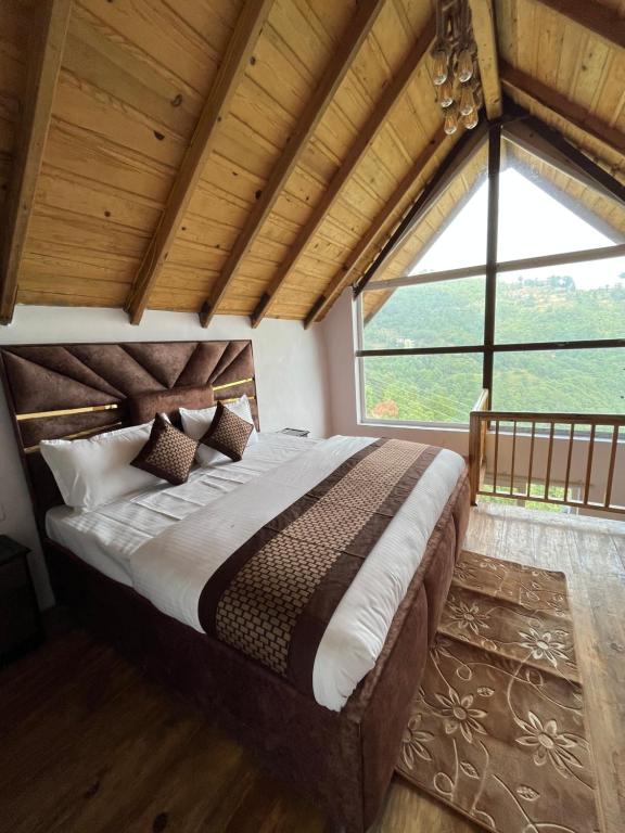 a bedroom with a large bed with a large window at THE FIG in Mukteswar