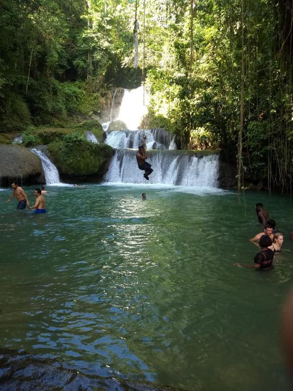 a group of people in the water in front of a waterfall at Hillside Sunrise, 2 Bed 2 Bath in Gated Community, close to beach, food, clubs & shopping Free Parking, Free Wi-Fi in Montego Bay