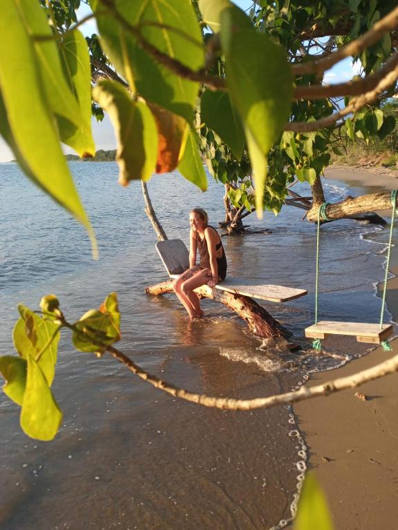 a man sitting on a tree branch on the beach at Hillside Sunrise, 2 Bed 2 Bath in Gated Community, close to beach, food, clubs & shopping Free Parking, Free Wi-Fi in Montego Bay