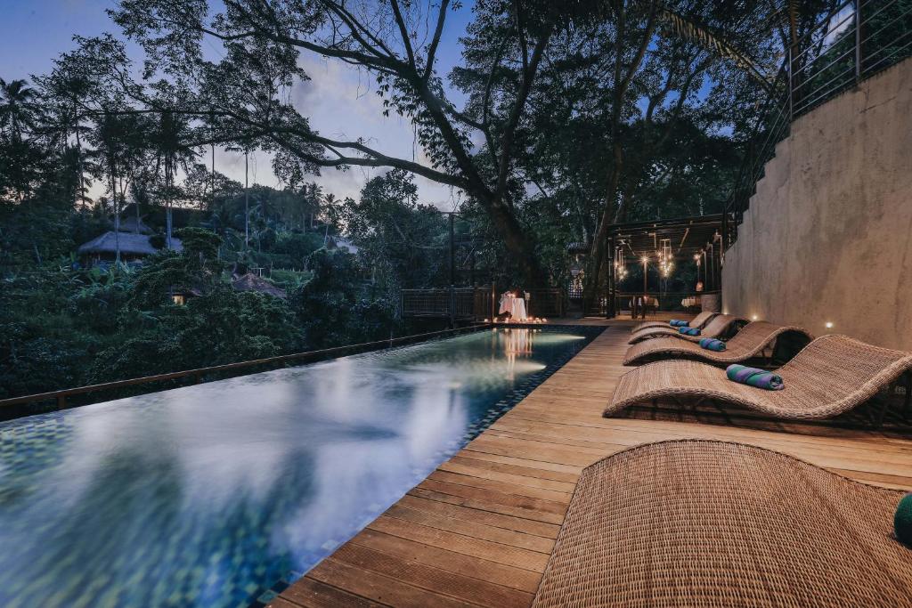 una piscina con tumbonas en una terraza de madera en The Sebali Resort, en Ubud