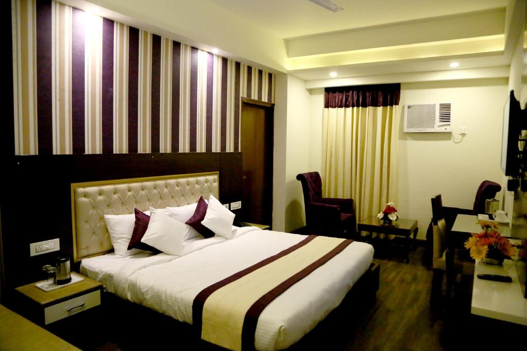 a hotel room with a large bed and chairs at Hotel S C Residency in Zirakpur