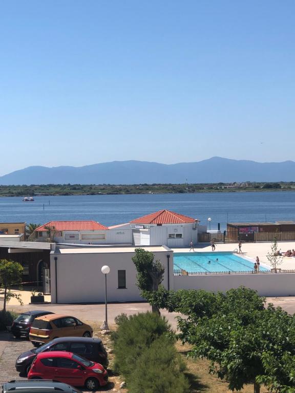 un bâtiment avec une piscine et des voitures garées dans un parking dans l'établissement Location coudalere, au Barcarès