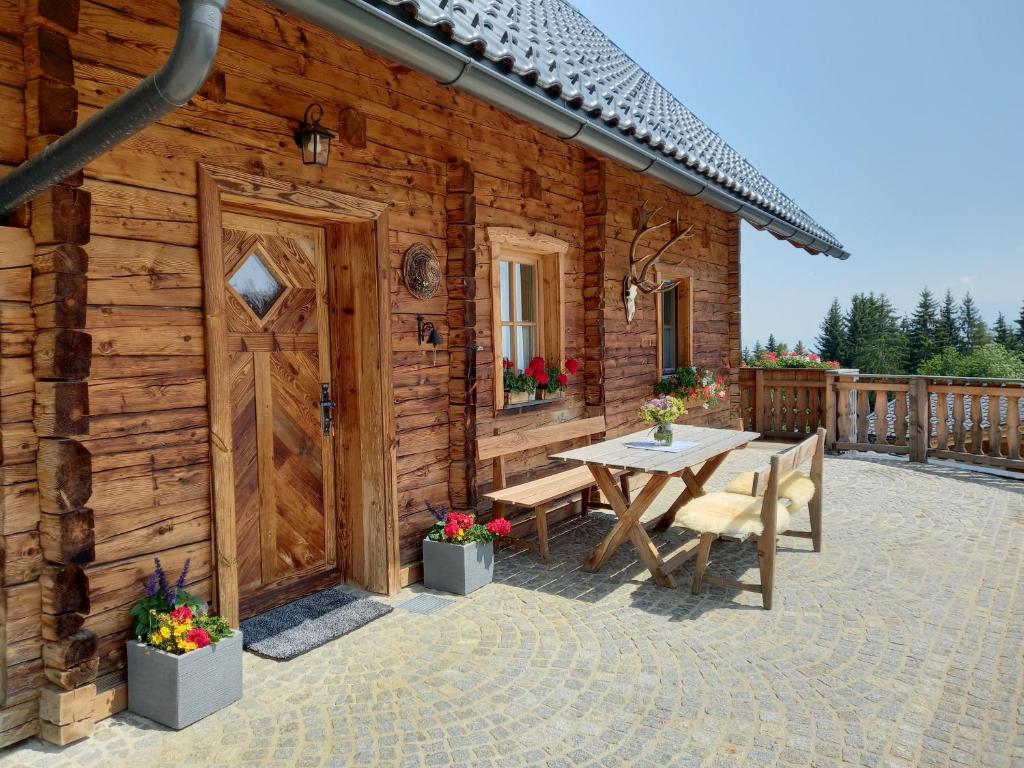 eine Holzhütte mit einem Tisch und einer Holztür in der Unterkunft Almchalet Schuster in Diex
