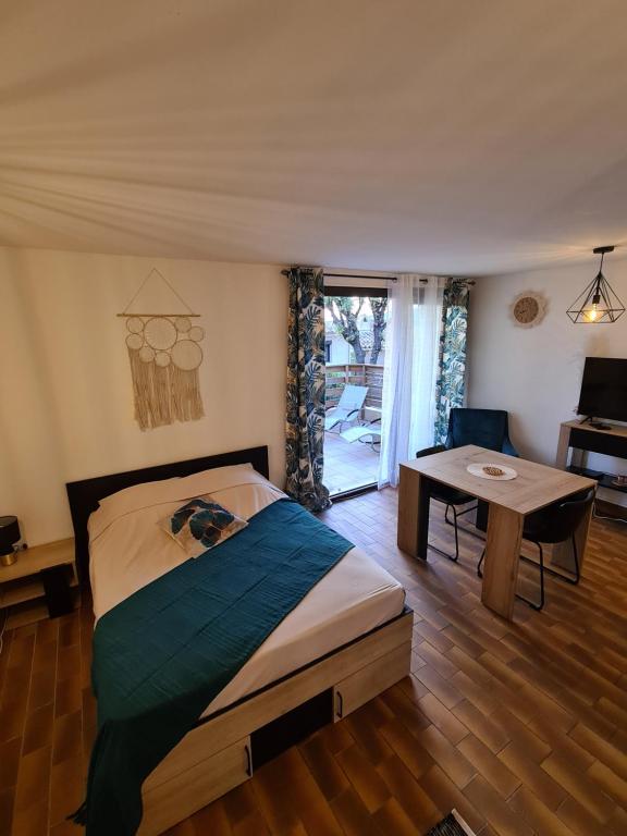 1 dormitorio con cama, mesa y ventana en Studio avec terasse vue mer en Porticcio