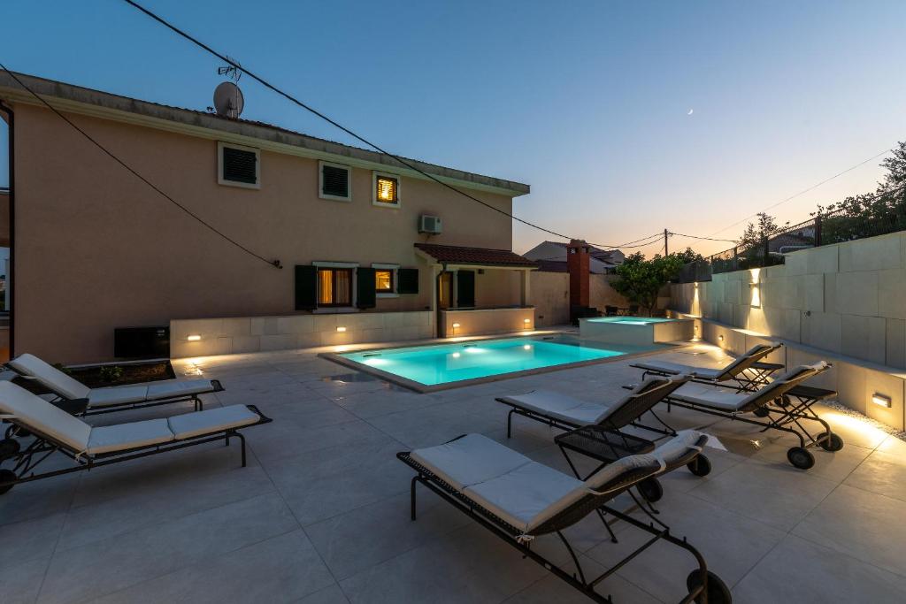 un patio con sillas y una piscina en Villa Lavandula with heated swimming pool, en Trogir