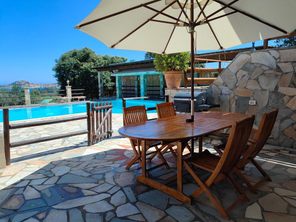 a table and chairs with an umbrella next to a pool at Casa del Duca Portoferraio in Portoferraio
