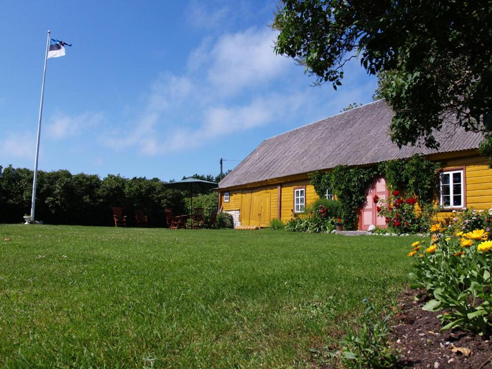 una casa amarilla y roja con un patio verde en Kusti Turismitalu, en Vilsandi