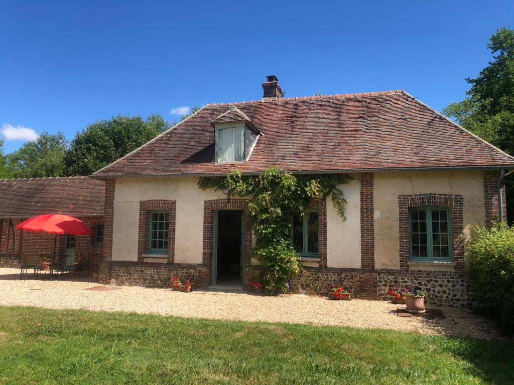 una vieja casa de ladrillo con una sombrilla roja en Le Rucher, en Bois-Normand-près-Lyre