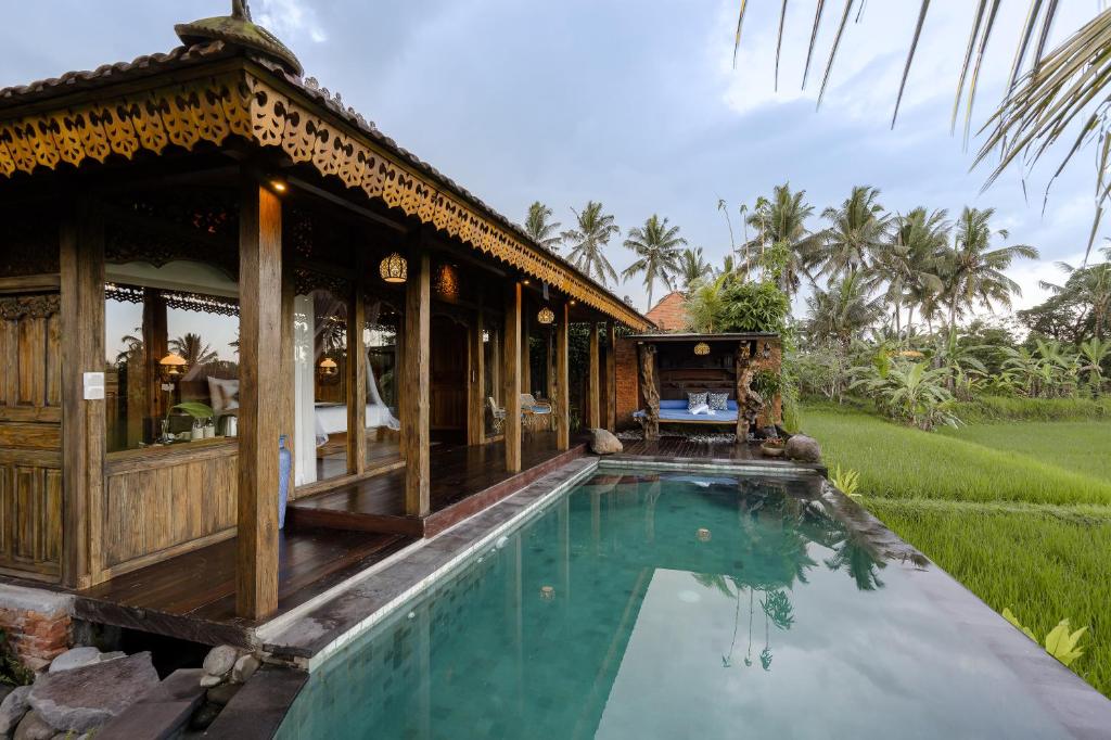 a villa with a swimming pool in front of a house at Airsania Ubud Antique Villas in Ubud