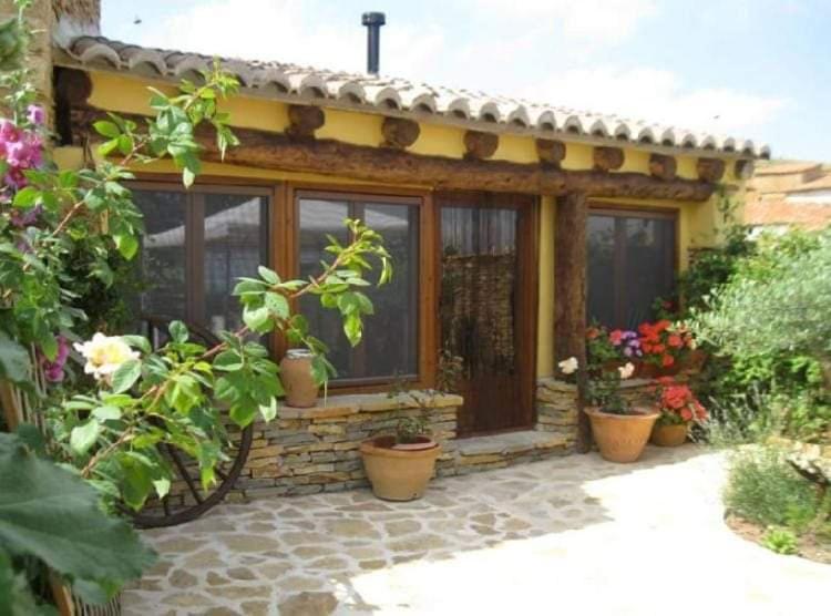 a house with potted plants sitting outside of it at Casa rural La antigua botiga in La Iglesuela del Cid