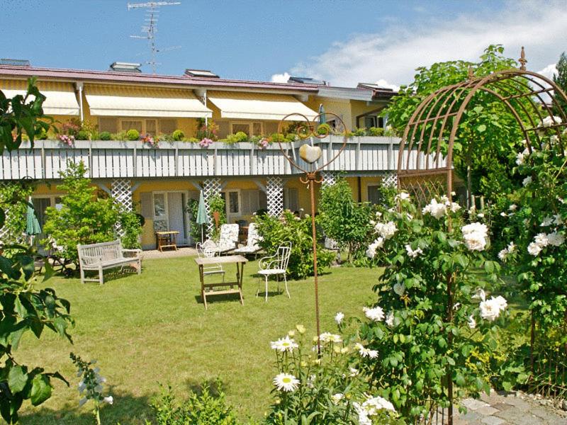 uma casa com um quintal com cadeiras e flores em Landhotel Herzberger garni Zimmer & Ferienwohnungen em Scheidegg