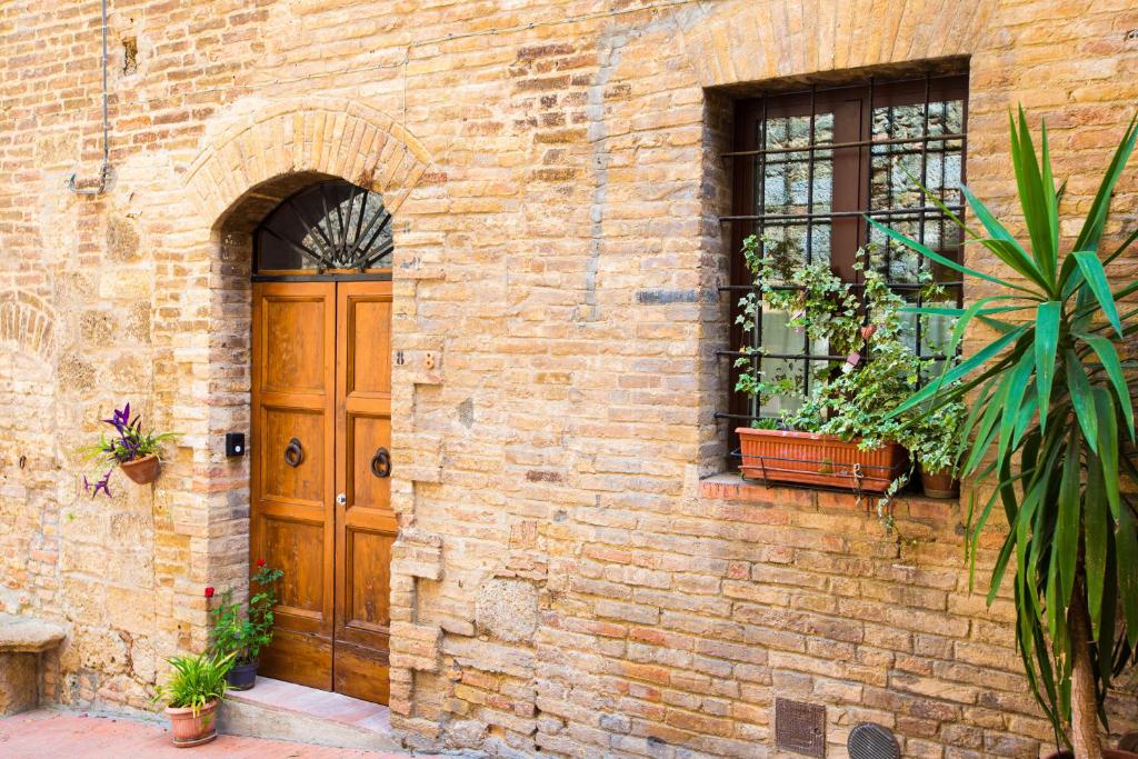 um edifício de tijolos com uma porta de madeira e uma janela em Il Capitello em San Gimignano