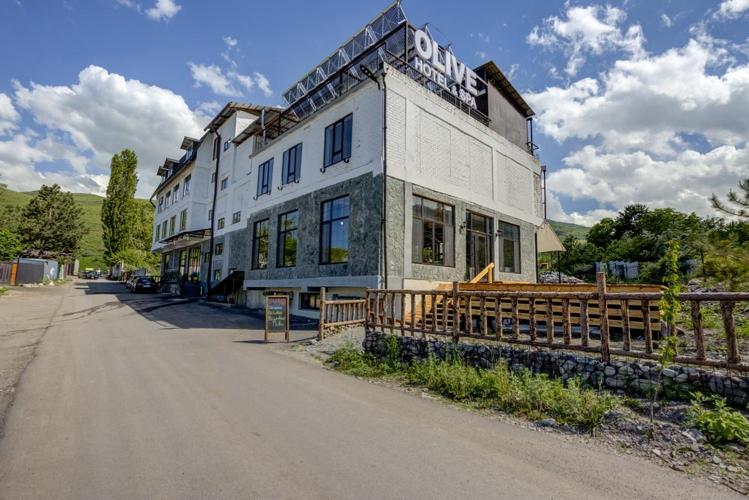 ein großes weißes Gebäude an der Seite einer Straße in der Unterkunft Olive Ala-Archa Hotel & SPA in Verkhnyaya Alaarcha