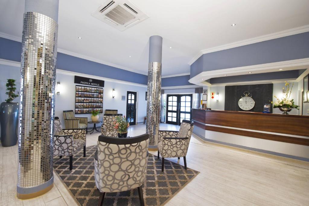un vestíbulo con una zona de espera con sillas y mesas en Hotel Thuringerhof en Windhoek