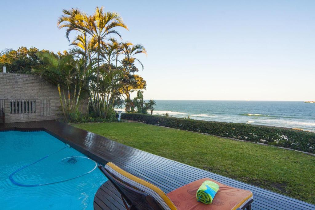 a swimming pool with chairs and a view of the ocean at Burnham House B&B in Durban