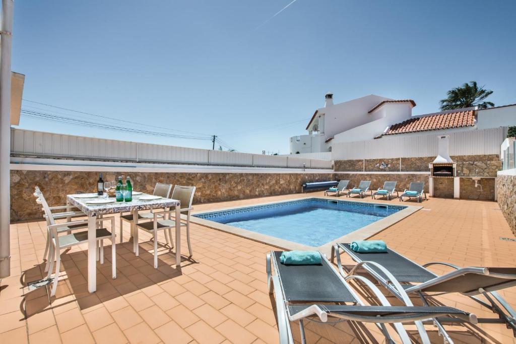 a patio with a table and chairs next to a pool at Felizalgarve by Algarve Villa Holidays in Albufeira