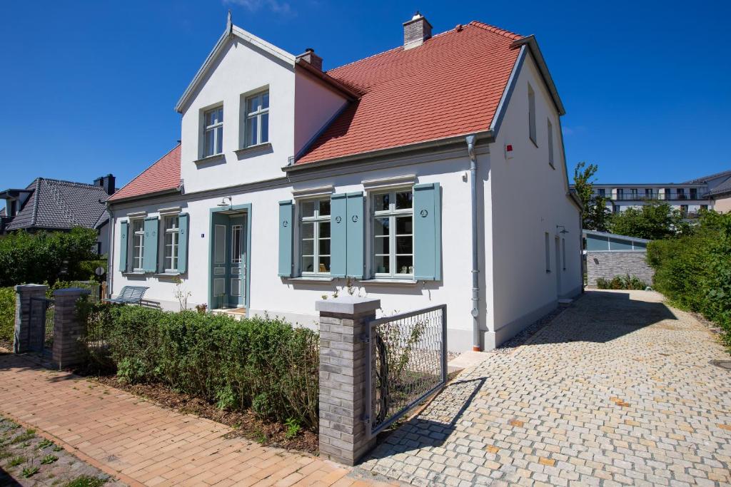 a white house with a red roof and a gate at Kapitänshaus Luv & Lee in Wustrow