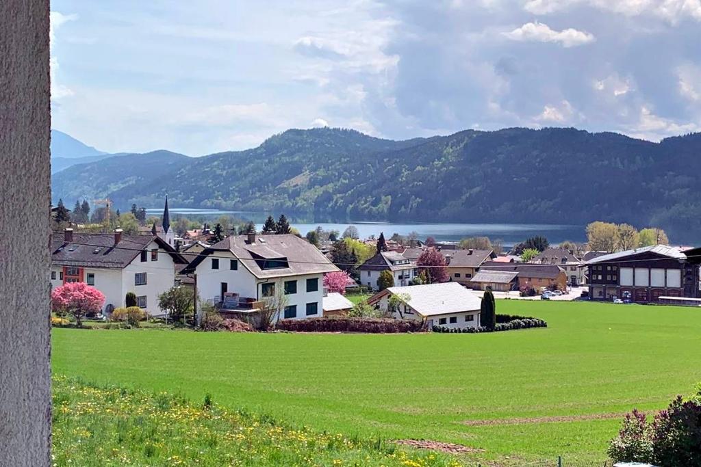 ein Dorf mit einem grünen Feld und Bergen im Hintergrund in der Unterkunft Maxi'Seeblick Apartments in Seeboden