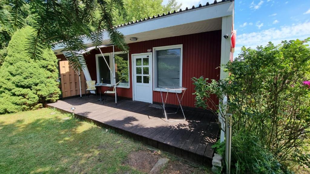ein kleines rotes Haus mit einer Holzveranda in der Unterkunft Bungalow (hälfte) Steuerbord Ahlbeck (Usedom) in Ahlbeck