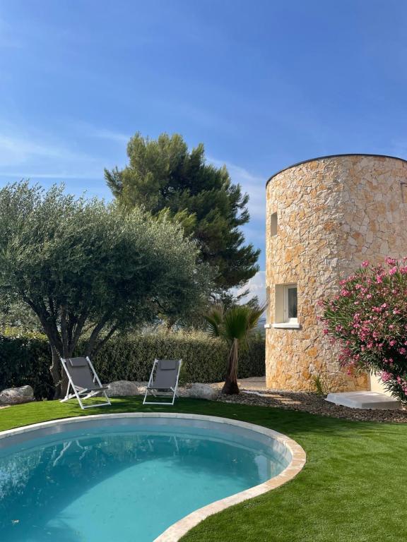 una piscina en un patio con 2 sillas y un edificio en La tour de Lézan en Lèzan