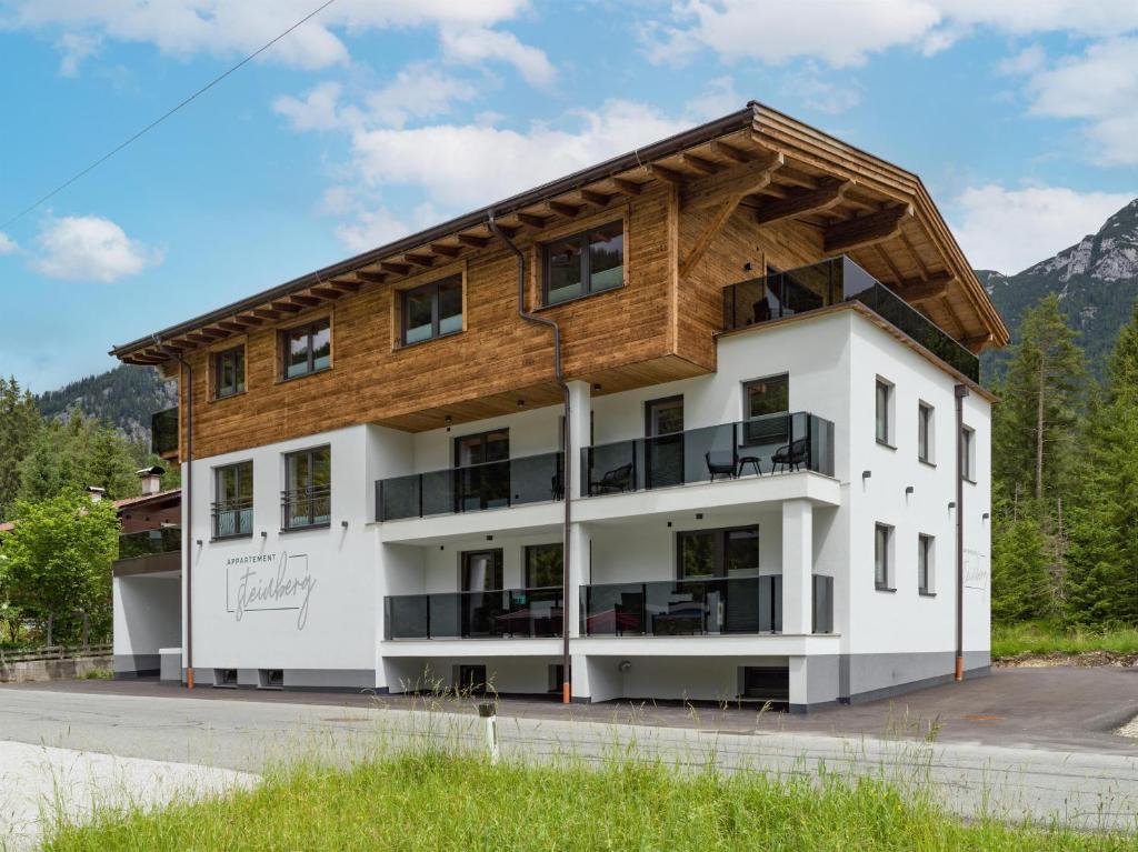 a large white building with a wooden roof at Appartements Steinberg in Steinberg am Rofan