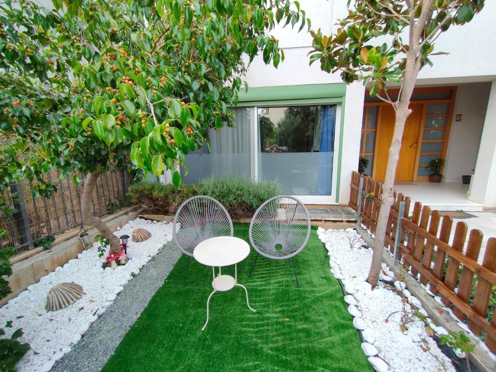 um jardim com duas cadeiras e uma mesa na relva em Serenity and Relaxing Studio em Kalamata