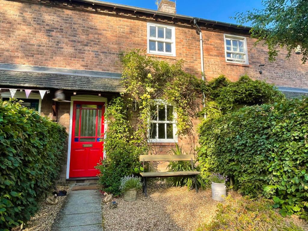 a brick house with a red door and a bench at Drake Cottage - riverside retreat, Jackfield, Ironbridge Gorge, Shropshire in Coalport