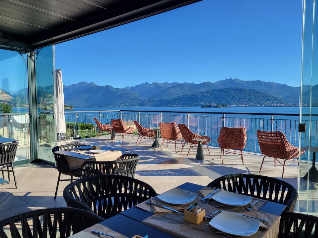 een patio met tafels en stoelen en uitzicht op het water bij Sempione Boutique Hotel in Stresa