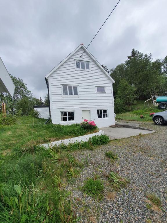 a white house with a driveway in a yard at Feriehus på Leirvåg/Austrheim 