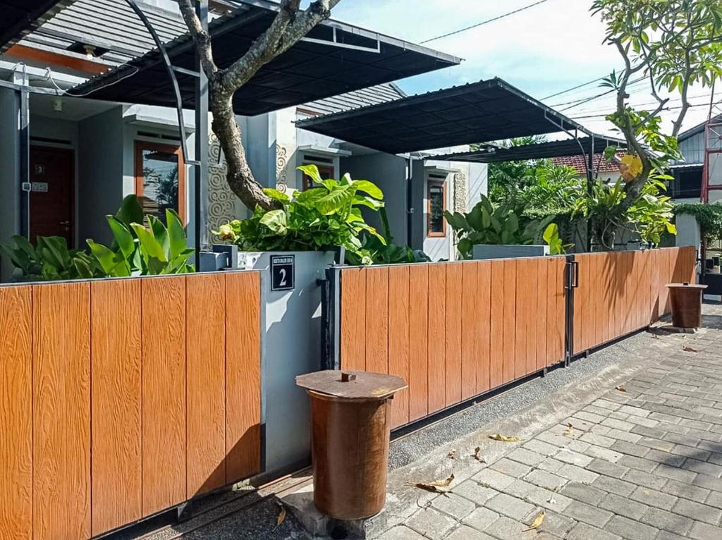 a fence with a trash can in front of a house at Andewi Homestay RedPartner - Minimum Stay 30 Nights in Pesanggaran
