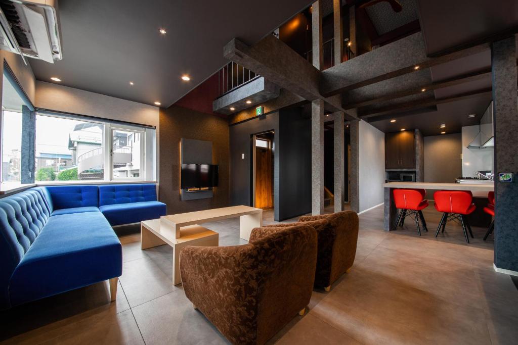 a living room with a blue couch and red chairs at THE BEEHIVE AIOI in Otaru