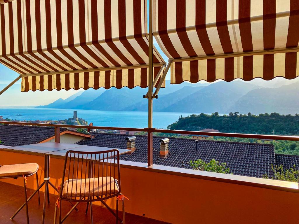 een balkon met een tafel en stoelen en een parasol bij Residence Kormorano in Malcesine