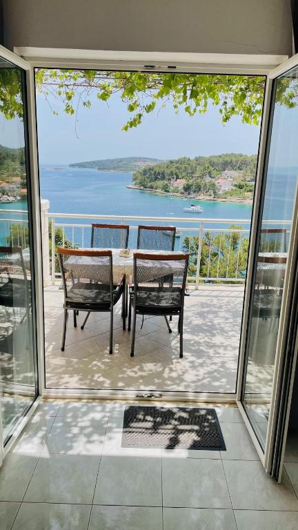 a table and chairs on a balcony with a view of the water at Apartments Danijela in Lumbarda