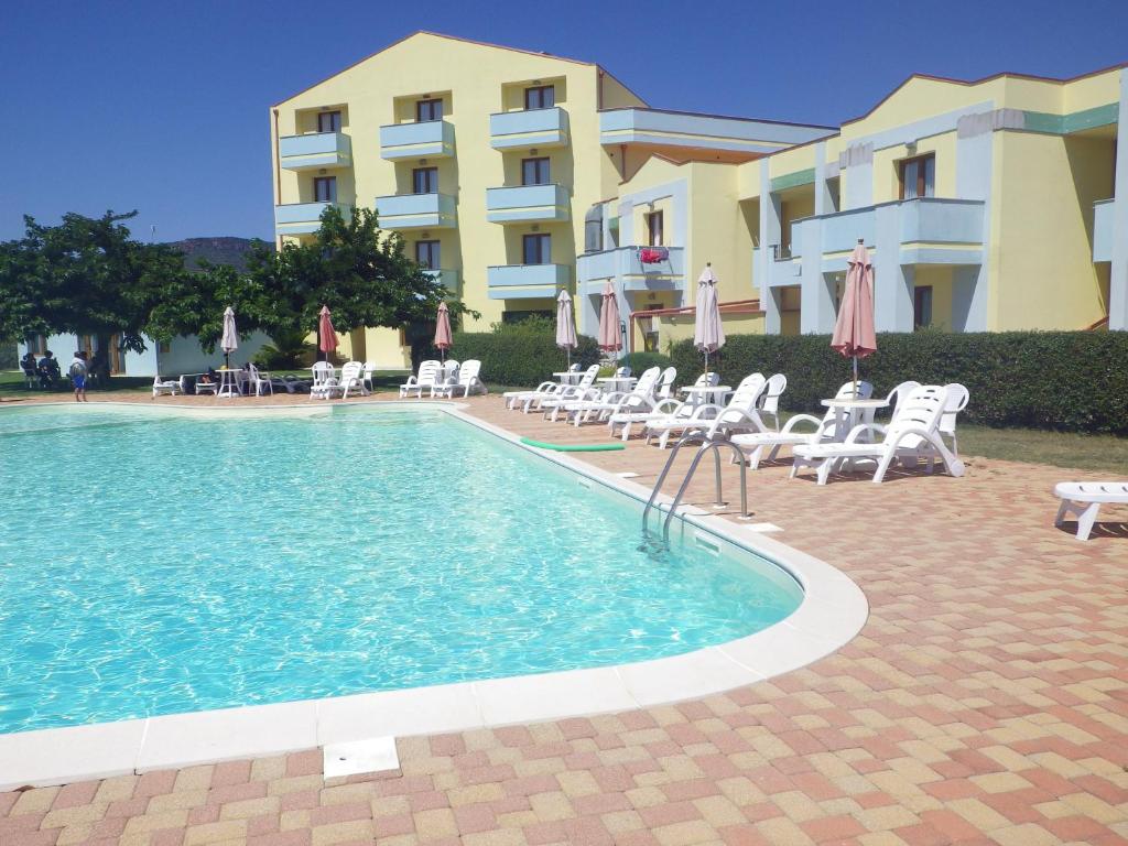 una piscina con sillas y sombrillas junto a un edificio en Resort Isola Rossa, en Bosa