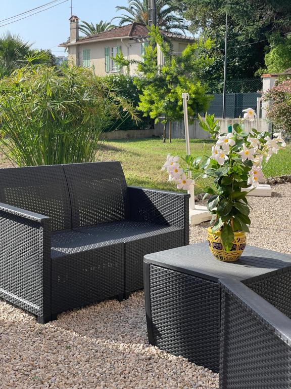 eine Terrasse mit 2 Korbstühlen und einem Tisch mit Pflanze in der Unterkunft Motel Esterel in Mandelieu-la-Napoule