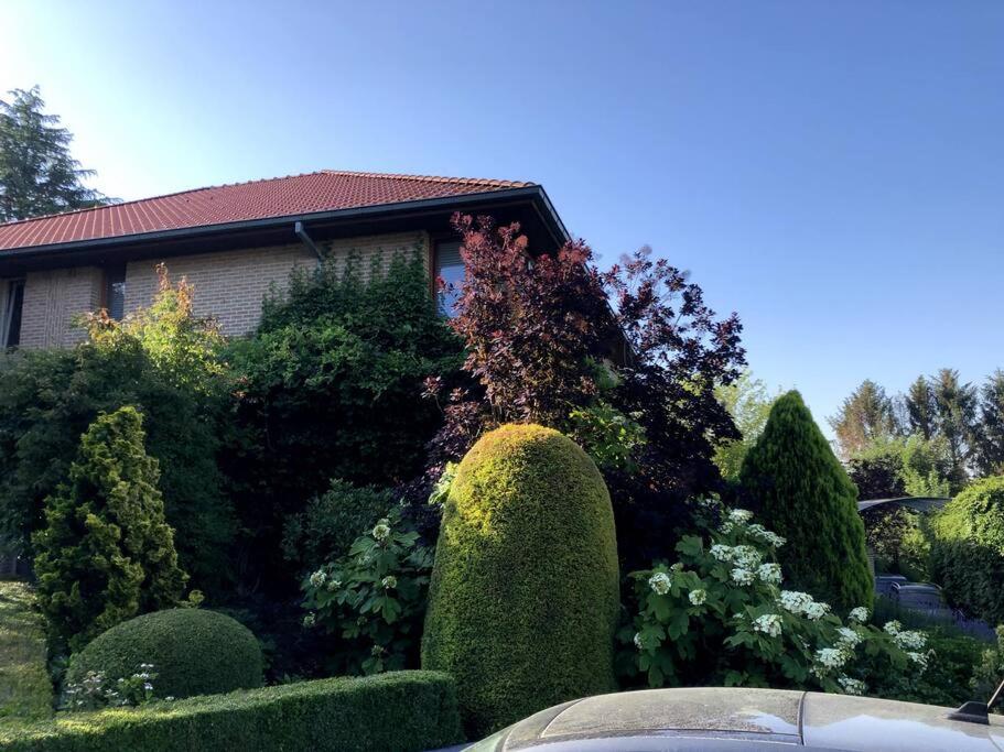 een huis met een tuin van struiken en bomen bij La Clé de la Forêt in Tervuren