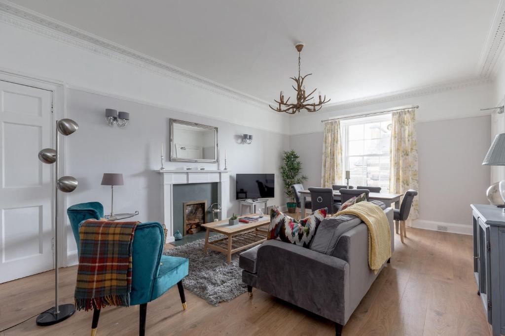 a living room with a couch and chairs and a tv at Glamorous flat near City Centre in Edinburgh